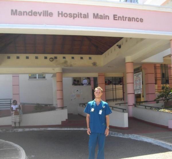 Foto de un interno médico frente al hospital donde realiza sus prácticas de Medicina en Jamaica. Interno médico posando para una foto fuera del hospital donde hace sus prácticas.